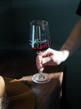 hand holding a glass of red wine on a wood table