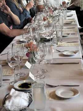 table set with white tablecloth, many glasses and white dishes