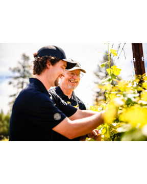 2 men looking at grapevines with smiles
