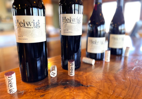 wood table top with wine bottles lined up with corks next to them