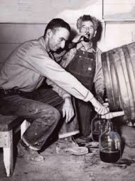 vintage photo of 2 menu pouring wine from a wine barrel into a jug.  One man is sipping wine from a wine glass