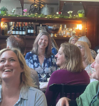 Women seated for lunch laughing with big smiles 