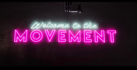 neon sign that reads welcome to the movement