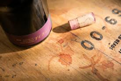 Wine bottle on wine barrel stained with wine drops